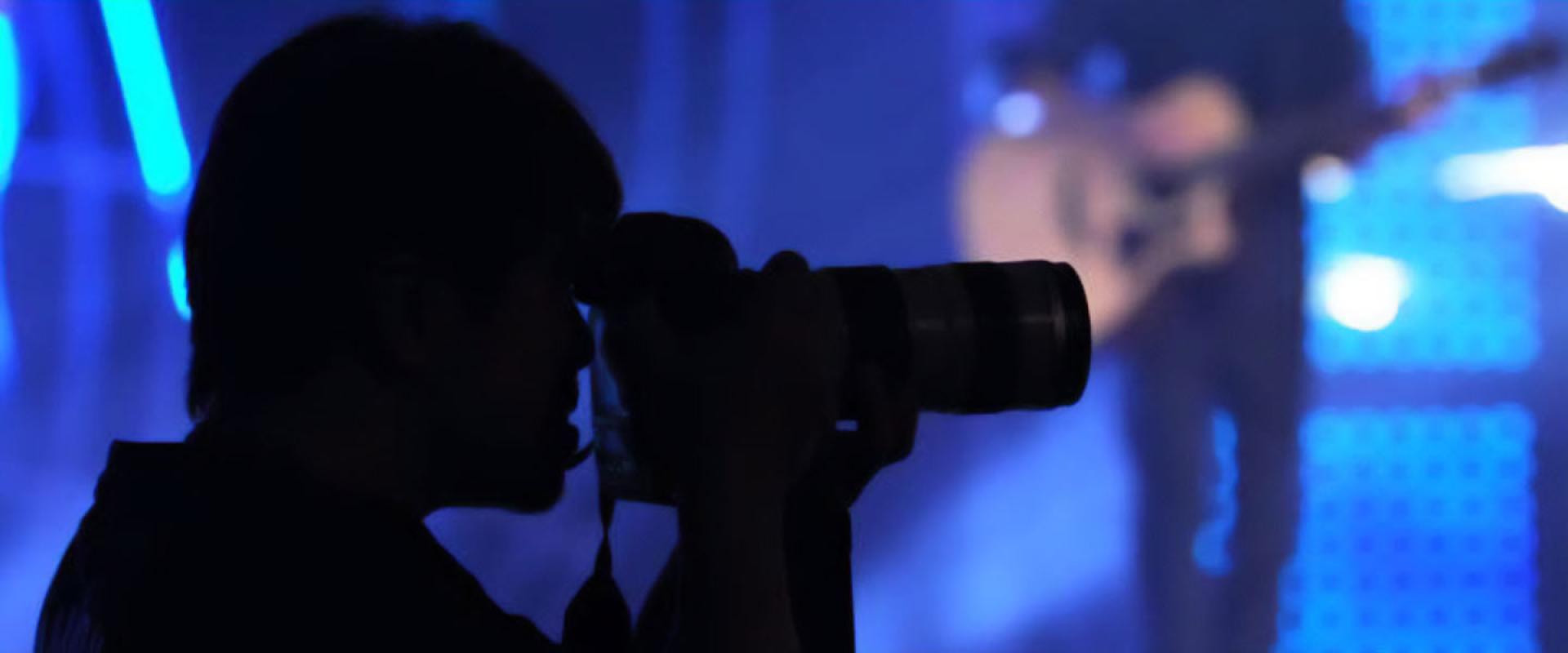 silhouette of a person pointing their camera towards the stage